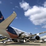 An AirJapan aircraft undergoing cargo loading and technical preparation on the tarmac at an international airport.