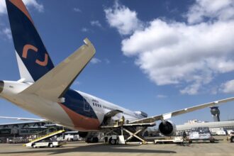 An AirJapan aircraft undergoing cargo loading and technical preparation on the tarmac at an international airport.