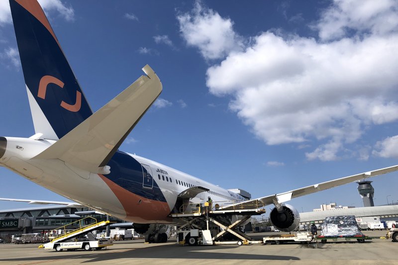An AirJapan aircraft undergoing cargo loading and technical preparation on the tarmac at an international airport.