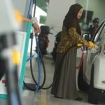 A woman refueling her car at a Malaysian petrol station benefiting from targeted national fuel subsidies.