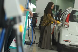 A woman refueling her car at a Malaysian petrol station benefiting from targeted national fuel subsidies.