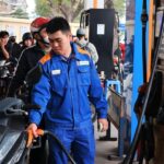 A worker fills a motorbike at a station as Vietnam extends fuel tax relief to stabilize energy prices in 2026.