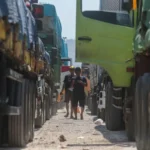 Drivers walk between rows of parked freight trucks during the holiday transport restrictions for national logistics.