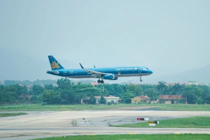 A Vietnam Airlines aircraft coming in for a landing at an airport with a lush green landscape in the background.