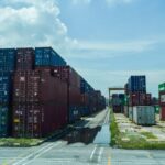Stacked shipping containers at a Malaysian port, illustrating the trade environment monitored by BNM for economic reviews.