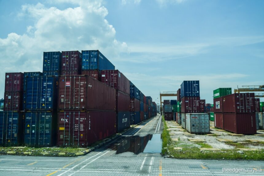 Stacked shipping containers at a Malaysian port, illustrating the trade environment monitored by BNM for economic reviews.