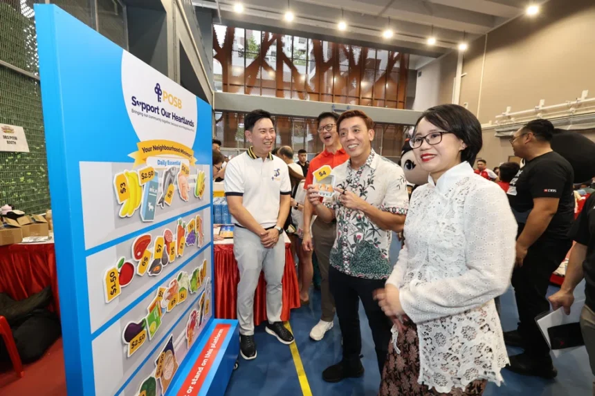 Participants at a DBS POSB community event showcasing daily essential price tags for the heartland support program.