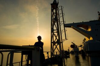 A worker on an offshore platform managing operations that support national energy subsidies and security.