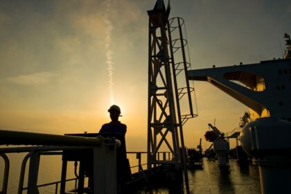 A worker on an offshore platform managing operations that support national energy subsidies and security.