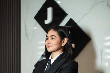 Jill Tolentino, President of JLT Group, posing in front of the corporate logo at the company headquarters.