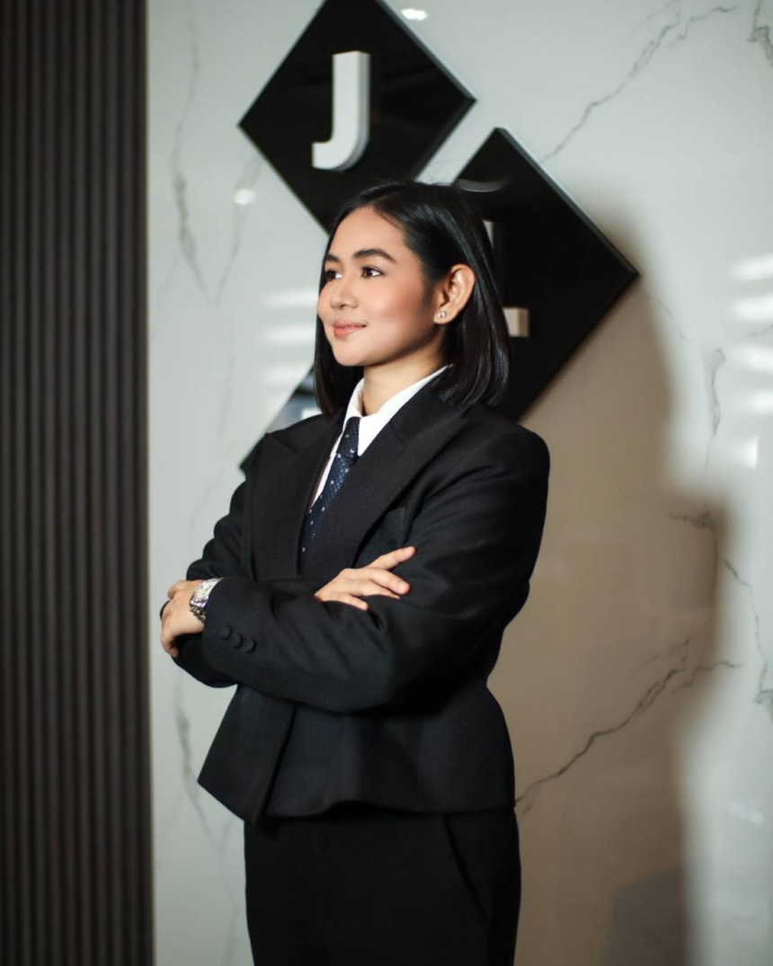 Jill Tolentino, President of JLT Group, posing in front of the corporate logo at the company headquarters.
