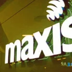 Close-up of the official Maxis logo illuminated on a store exterior in Malaysia.