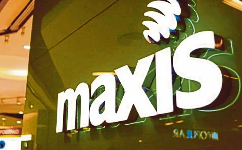 Close-up of the official Maxis logo illuminated on a store exterior in Malaysia.