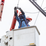 Utility workers in a bucket truck performing maintenance on power lines to ensure service reliability for Meralco.