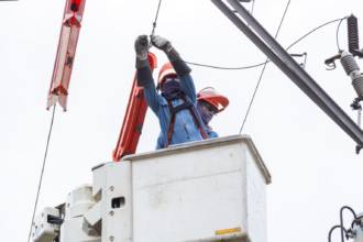 Utility workers in a bucket truck performing maintenance on power lines to ensure service reliability for Meralco.