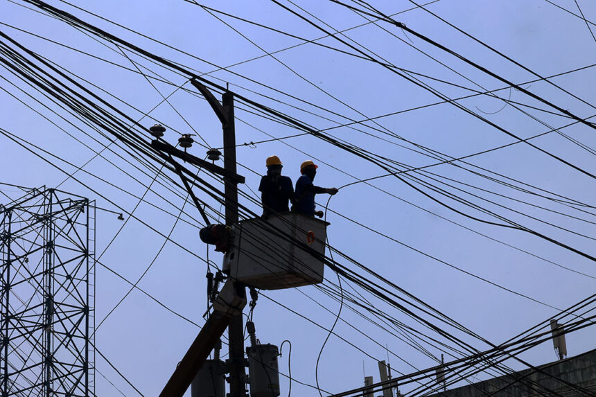 Maintenance workers on power lines, illustrating infrastructure costs monitored by the central bank.
