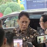 Minister Purbaya Yudhi Sadewa wearing a batik shirt while speaking to journalists during a media briefing in Jakarta.