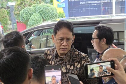 Minister Purbaya Yudhi Sadewa wearing a batik shirt while speaking to journalists during a media briefing in Jakarta.