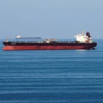 Oil tankers idle in open water as OPEC+ production quotas are discussed amidst regional maritime disruptions.