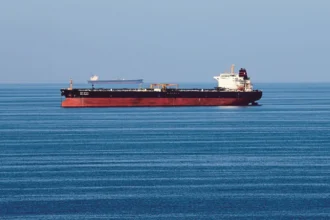 Oil tankers idle in open water as OPEC+ production quotas are discussed amidst regional maritime disruptions.