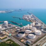 An aerial view shows a coastal storage terminal for oil and gas, highlighting critical regional energy infrastructure.