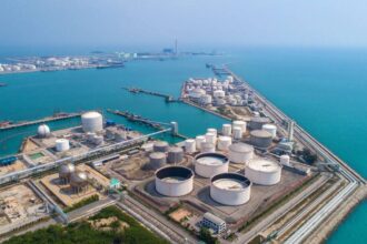 An aerial view shows a coastal storage terminal for oil and gas, highlighting critical regional energy infrastructure.