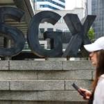 A pedestrian walks past the SGX building in Singapore, where companies listed on the STI are traded daily.