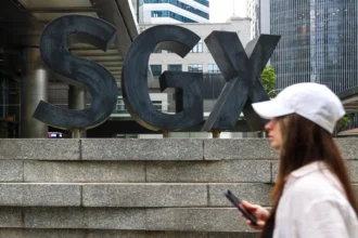 A pedestrian walks past the SGX building in Singapore, where companies listed on the STI are traded daily.