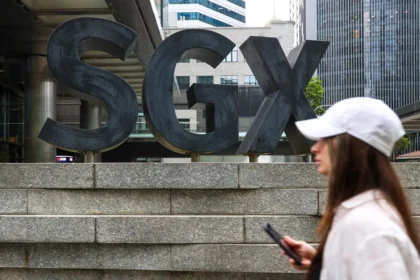 A pedestrian walks past the SGX building in Singapore, where companies listed on the STI are traded daily.