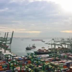 Aerial view of Singapore port terminals where slow steaming vessels arrive to manage fuel costs and trade flow.