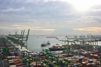 Aerial view of Singapore port terminals where slow steaming vessels arrive to manage fuel costs and trade flow.