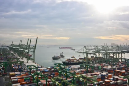 Aerial view of Singapore port terminals where slow steaming vessels arrive to manage fuel costs and trade flow.