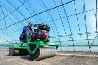 A farmer operating machinery inside a greenhouse, illustrating industrial agricultural growth within The Philippines economy.