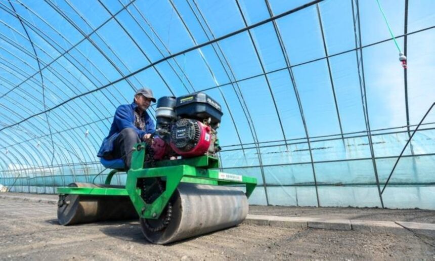 A farmer operating machinery inside a greenhouse, illustrating industrial agricultural growth within The Philippines economy.
