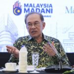 Prime Minister Anwar Ibrahim gestures during a conference, detailing financial support programs intended for small traders.