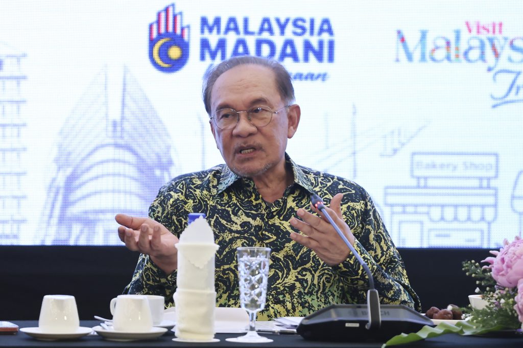 Prime Minister Anwar Ibrahim gestures during a conference, detailing financial support programs intended for small traders.