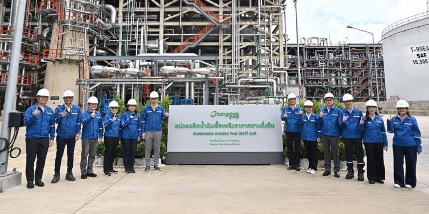 A group of officials in hard hats stands in front of the BCP sustainable aviation fuel industrial plant.