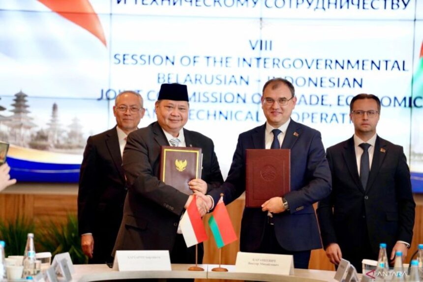 Indonesian and Belarusian officials shake hands while holding signed trade agreements at a joint commission meeting.