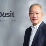 A professional studio portrait of Chanin Donavanik next to the grey Dusit International corporate logo.