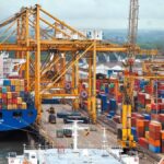 Container ship at a busy port, loading electronics for export.