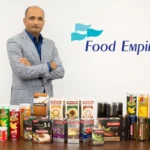 CEO Sudeep Nair posing with various Food Empire beverage and snack products next to the company logo.