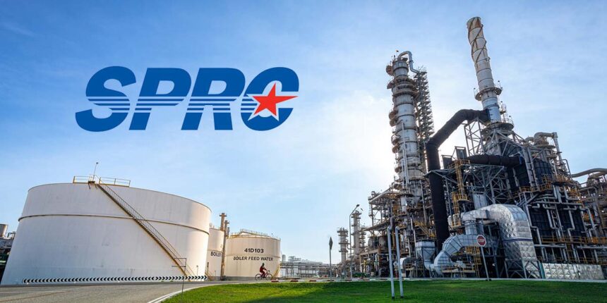 Industrial view of the SPRC oil refinery complex featuring large storage tanks and processing towers under a clear sky.
