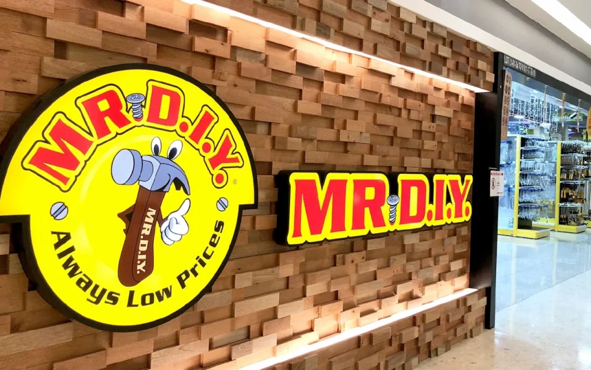 A storefront featuring the yellow and red Mr. DIY logo on a textured wood wall with bright store lighting.