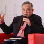 Minister Gan Kim Yong speaking into a microphone during a financial hub panel discussion on global AI strategies.