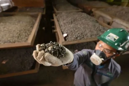 A worker holding a handful of processed ore samples within a production facility of the nickel corridor axis.