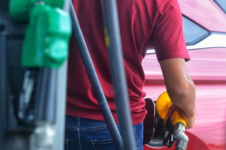 A gas station worker refueling a car amid recent weekly adjustments to domestic commercial retail fuel prices.