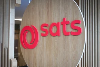 The company logo for SATS displayed on a wooden circular sign