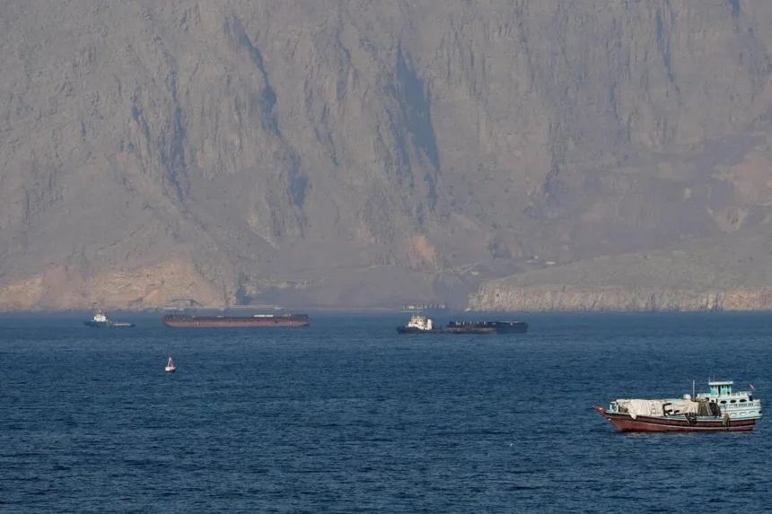 Vessels navigating critical oil shipping lanes near the Strait of Hormuz against a rugged mountainous coastline.