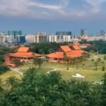 Aerial view of the lush greenery and clubhouse at Saujana Resort set against a modern city skyline.