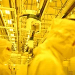Workers in cleanroom suits producing AI-Related Electronics.